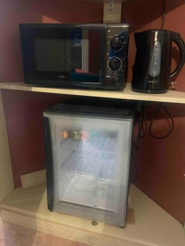 un four micro-ondes et une télévision assise sur une étagère. dans l'établissement La suite 2 pièces lit queen size entrée privée, à Nîmes