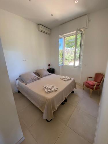 a white bedroom with a bed and a window at Villa Nicole avec Spa professionnel in Carry-le-Rouet