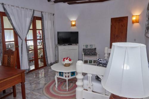 a living room with a table and a television at Cosy Cottage Marine Park at Malindi Beach in Malindi