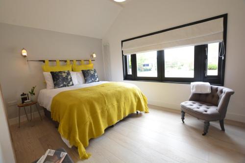 a bedroom with a bed and a chair and a window at Milk Parlour in Spexhall