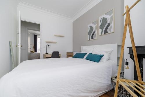 une chambre avec un lit blanc avec des oreillers bleus dans l'établissement Flexliving - room - Caulaincourt, à Paris