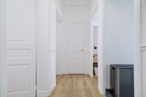 un couloir avec des portes blanches et un plancher en bois dans l'établissement Flexliving - room - Caulaincourt, à Paris