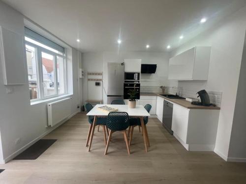 une cuisine blanche avec une table et des chaises dans l'établissement Maison de pêcheur à Rosendaël, à Dunkerque