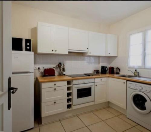 une cuisine avec des armoires blanches et une laveuse et une sécheuse dans l'établissement Marina l Appuntamento, à Aigues-Mortes