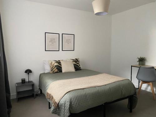 a bedroom with a bed with two pictures on the wall at Le nid douillet à 500m de la gare in Évreux