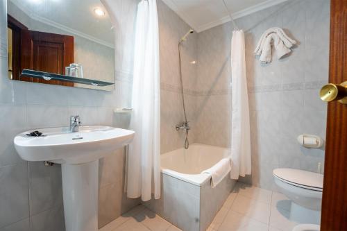 ein Bad mit einem Waschbecken, einem WC und einer Dusche in der Unterkunft Hotel Restaurante GBC Isape in Arcade