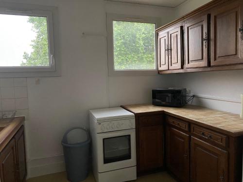 - une cuisine équipée d'un four avec plaques de cuisson blanches à côté de 2 fenêtres dans l'établissement Le nid douillet à 500m de la gare, à Évreux