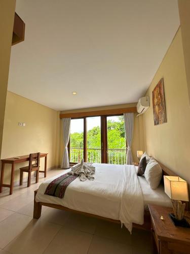 a bedroom with a large bed and a balcony at Oka's Guest House Canggu in Canggu