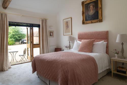 a bedroom with a bed with a painting on the wall at The Clock Tower & Dairy - Two x 2 Bed Barns with Indoor Pool in Checkendon