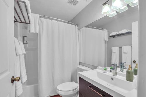 a white bathroom with a toilet and a sink at Blissful Haven - Updated & Fully Equipped Condo in Gainesville