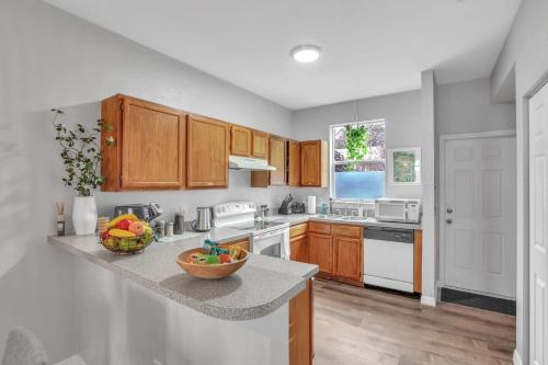 a kitchen with wooden cabinets and a bowl of fruit on a counter at The Prairie at Brighton - UF , Pool , Workspace in Gainesville