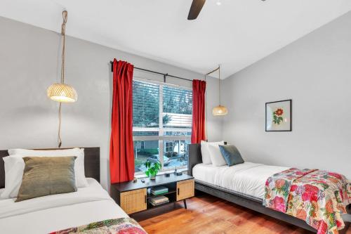 two beds in a room with red curtains at Blissful Haven - Updated & Fully Equipped Condo in Gainesville