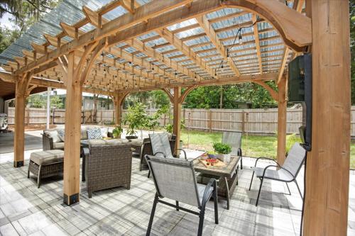 a wooden pavilion with a table and chairs on a patio at The Canopy on 10th - Game Room , Pets , Pergola in Gainesville