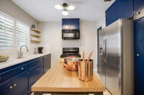 a kitchen with blue cabinets and a stainless steel refrigerator at The Canopy on 10th - Game Room , Pets , Pergola in Gainesville
