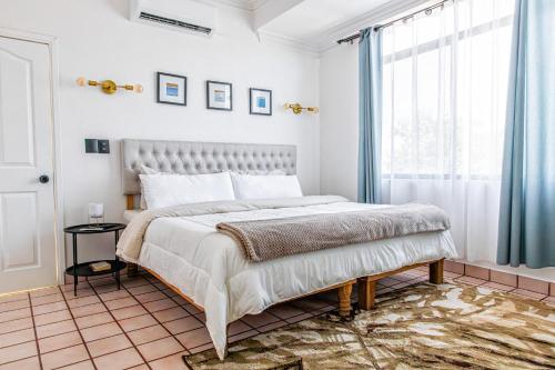a white bedroom with a large bed and a window at Casa Palma in La Paz