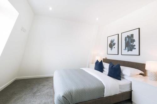 イプスウィッチにあるBudget 1 Bed Top Floor Apartment in Ipswichの白いベッドルーム(青い枕の大型ベッド付)