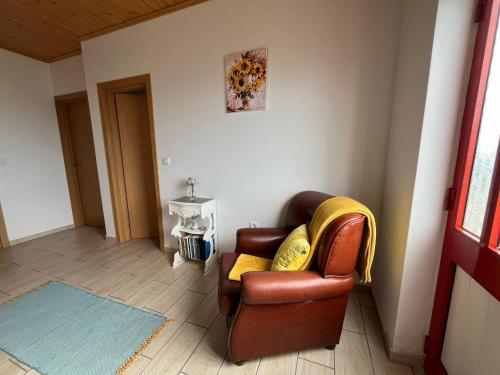 a living room with a brown leather chair with yellow pillows at Sunflower Guest House - Madalena - Pico in São Caetano