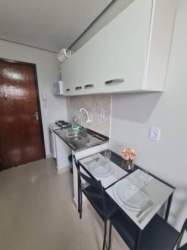 a small kitchen with a sink and a counter with chairs at Kitnet304 centro,c linda vista janela, tv smart in Montes Claros