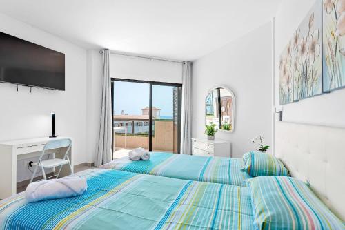 a white bedroom with a blue bed and a window at Atlantic Sky Panorama in Costa Del Silencio