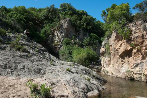 a man sitting on a rock next to a river at Hotel I Menhirs in Annunziata