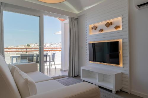 a living room with a white couch and a tv at MUPA Apartments in Albufeira