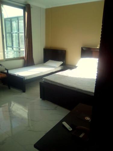 two beds sitting in a room with a window at Hotel La Orilla Muzaffarabad in Muzaffarabad