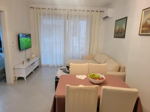 a living room with a table and chairs and a television at Henri's Apartments Vlore in Vlorë