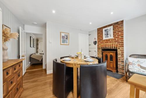 a dining room with a table and chairs and a fireplace at 2-Bedroom Stylish & Gorgeous, Cosy Westgate Cottage Retreat, Central Winchester, Free On-Street Parking Permit, with Garden, Close to Cathedral - Sleeps 6, Pets are Welcome - by Blue Puffin Stays in Winchester