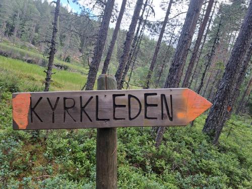 a wooden sign that reads kyrkkleden in a forest at Guesthouse Nature Trails Sweden in Övre Älgestad