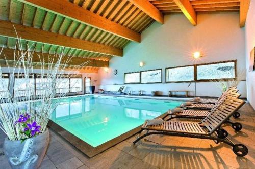 - une grande piscine avec 2 chaises longues à côté dans l'établissement Appartements Ski Spa & Confort Orelle-3 vallées, à Orelle