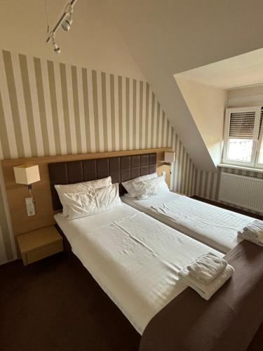 a bedroom with a large bed with white sheets at Hotel Ortel GmbH in Besigheim