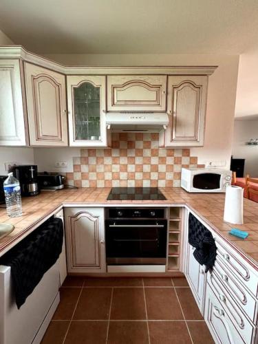 une cuisine avec des armoires blanches et un four à plaques de cuisson dans l'établissement Charmante Maison de Montagne, à Benqué