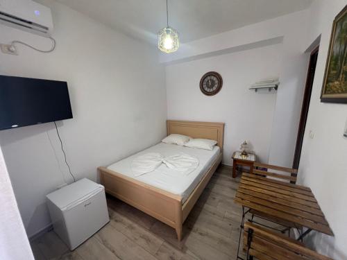 a small bedroom with a bed and a tv at Room Click inn in Gjirokastër