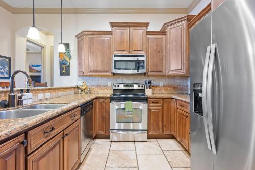 a kitchen with wooden cabinets and a stainless steel refrigerator at The Condo at Coral Springs Resort in Hurricane