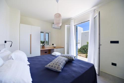 a bedroom with a blue bed and a large window at Ariti's Villas 2 - Naxos in Naxos Chora
