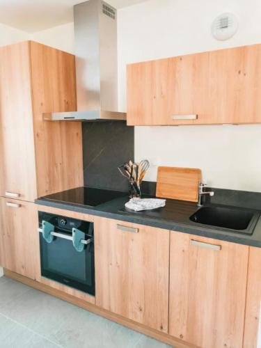 une cuisine avec des armoires en bois et un comptoir noir dans l'établissement Bel appartement 3 pièces, 62 m2, 2 à 6 personnes, très calme, aux Gets