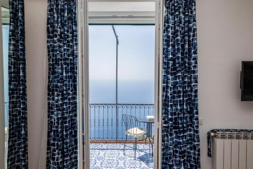a glass door leading to a balcony with a chair at Rosy's Room in Furore