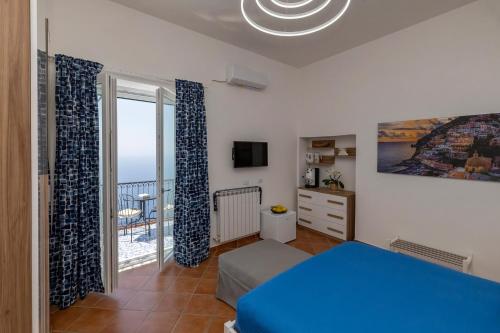 a bedroom with a blue bed and a balcony at Salvo's House in Furore