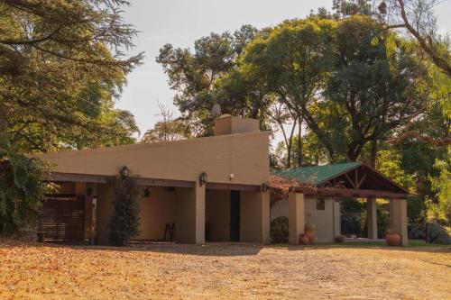ein Haus mit Garage und Bäumen im Hintergrund in der Unterkunft Casa en Ascochinga privado. Sierras de Córdoba in Ascochinga