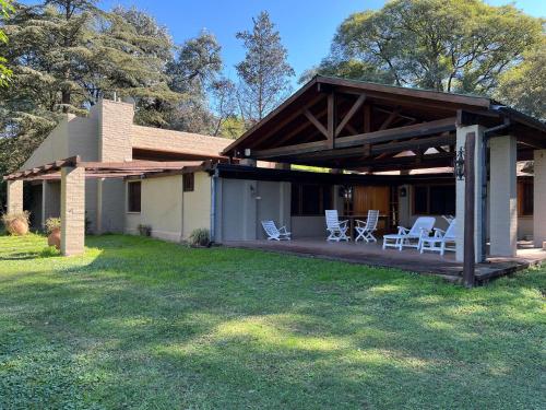 ein Haus mit einer überdachten Veranda mit Stühlen darauf in der Unterkunft Casa en Ascochinga privado. Sierras de Córdoba in Ascochinga