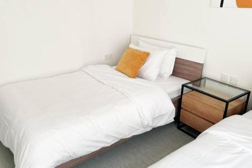a bedroom with two beds and a glass table at Near AlQurum Beach, Free Parking in Muscat