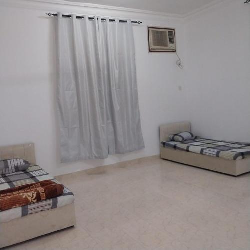 two beds sitting in a room with a window at Villa 91 in Salalah