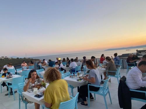 a group of people sitting at tables at a restaurant at Ugem in Seferihisar