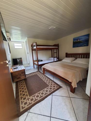 a bedroom with two beds and a table with a rug at Pousada Lua Cheia in Ilha do Mel