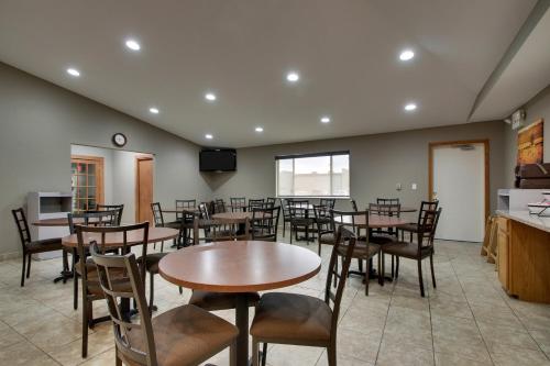 a dining room with tables and chairs and a tv at EverSpring Inn & Suites in Oskaloosa