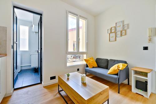 ein Wohnzimmer mit Sofa und Tisch in der Unterkunft Le Cœur des Antiquaires - 5 min de Paris in Saint-Ouen