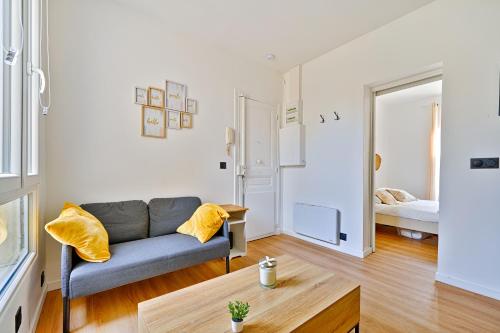 ein Wohnzimmer mit einer Couch und einem Bett in der Unterkunft Le Cœur des Antiquaires - 5 min de Paris in Saint-Ouen