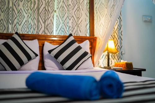 a bedroom with a bed with two pillows and a lamp at Nice View Lodge in Sigiriya