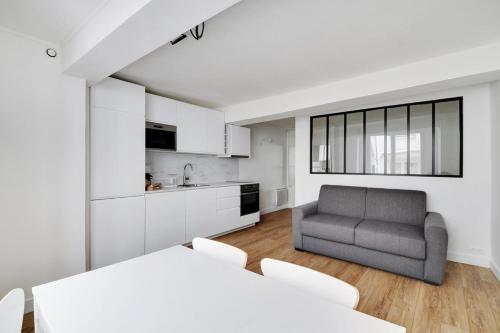 Il comprend un salon avec un canapé gris et une cuisine. dans l'établissement Flexliving - Studio - Saint Antoine, à Paris
