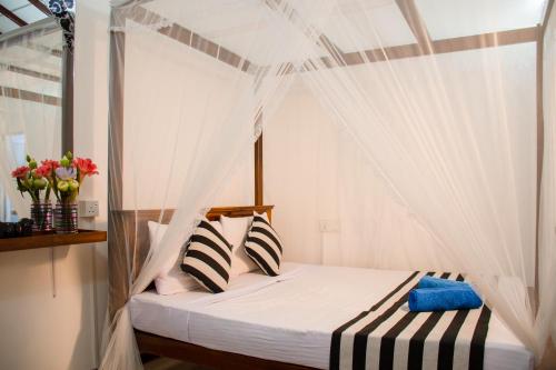 a bedroom with a canopy bed with white curtains at Nice View Lodge in Sigiriya